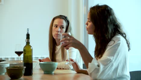 Two-cheerful-women-talking-while-drinking-wine